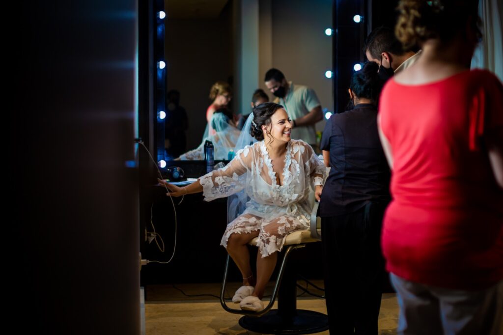 Photo of bride getting ready at the spa salon dressed in a white silk robe with some girlfriends. this is one of the most important steps to destination wedding planning