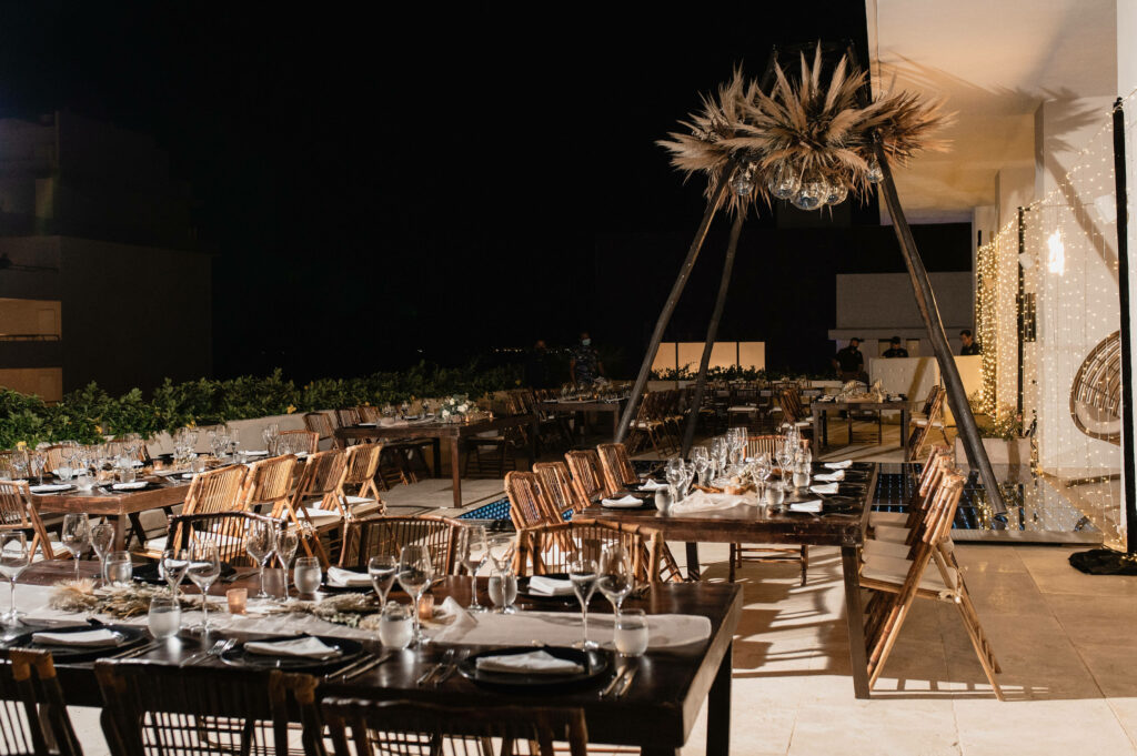 Destination wedding reception with rectangular tables, bamboo chair and wall of lights on the Piano bar terrace at the Majestic Elegance Costa Mujeres