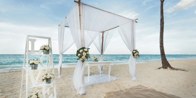 Destination wedding beach ceremony set-up with white linen, bouquet and white ceremony table at Riu Dunamar