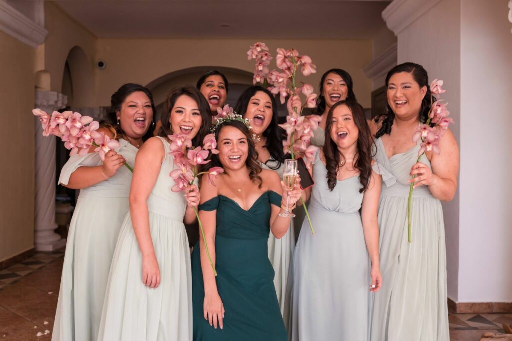 bridesmaids dressed in green and holding pink orchids