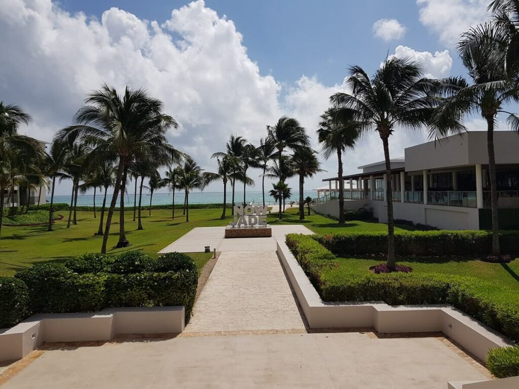 main courtyard area with now jade sign, palm trees and the ocean in the distance