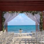 Destination wedding ceremony set-up at pergola with green and whitel flowers and ocean view at Dreams Jade