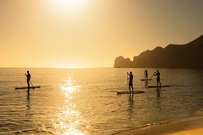 people paddleboarding on the ocean in the bay at cabo san lucas