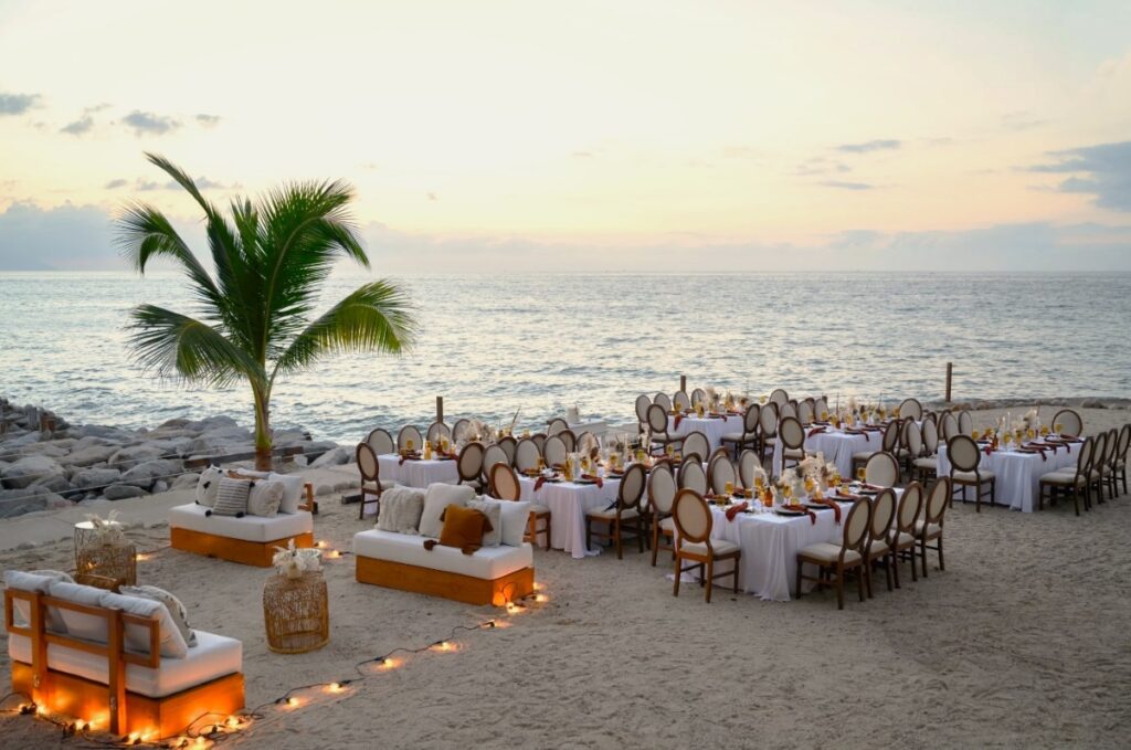 A beach wedding reception with elegant furniture and the ocean at the back