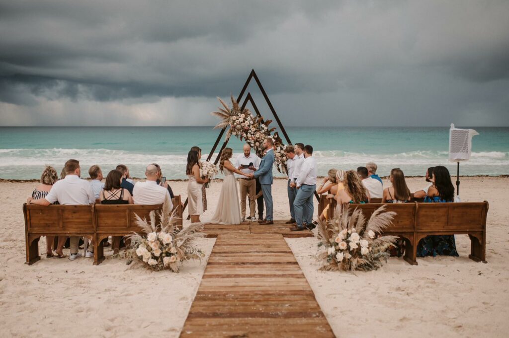 a beach wedding ceremony with the ocean and the back and some storm clouds afar