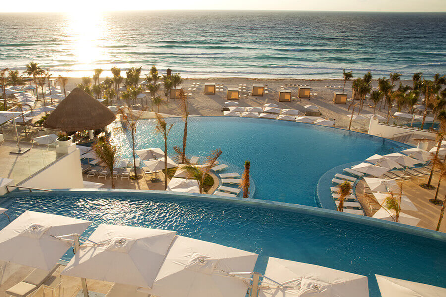 view of two pools with beach in the distance at leblanc resort in cancun