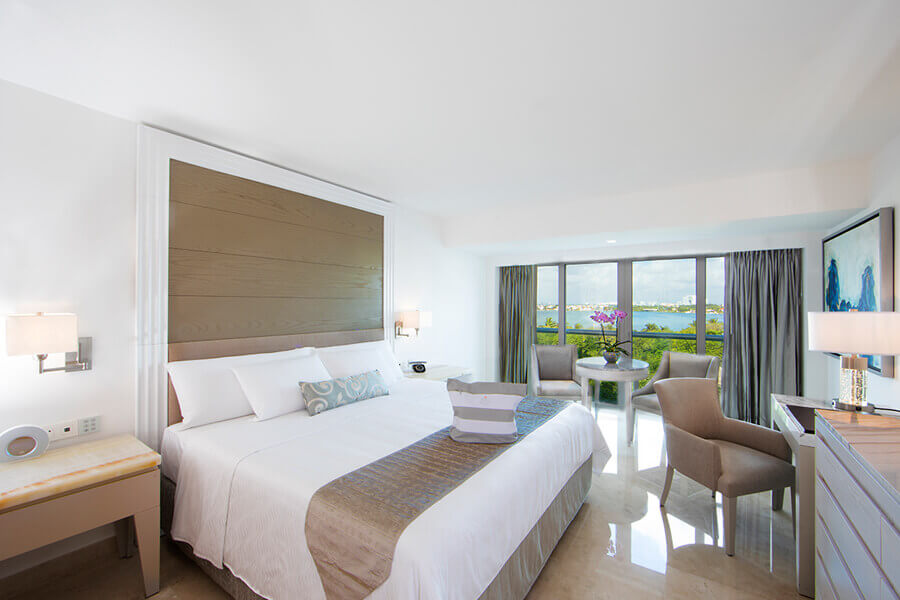 hotel room interior with king bed, white and tan decor
