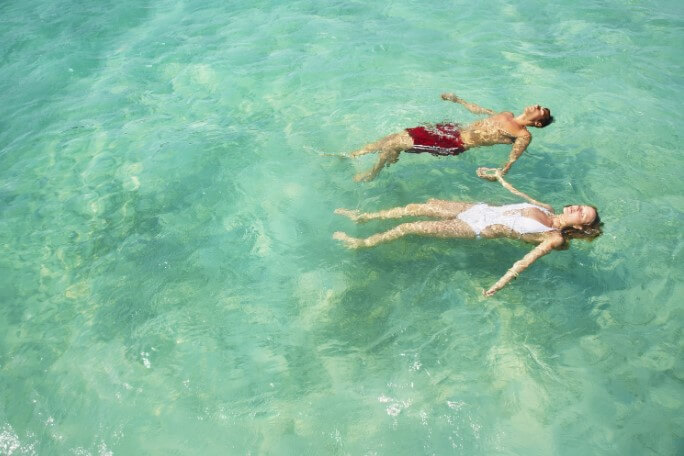 couple holding hands and floating in the ocean