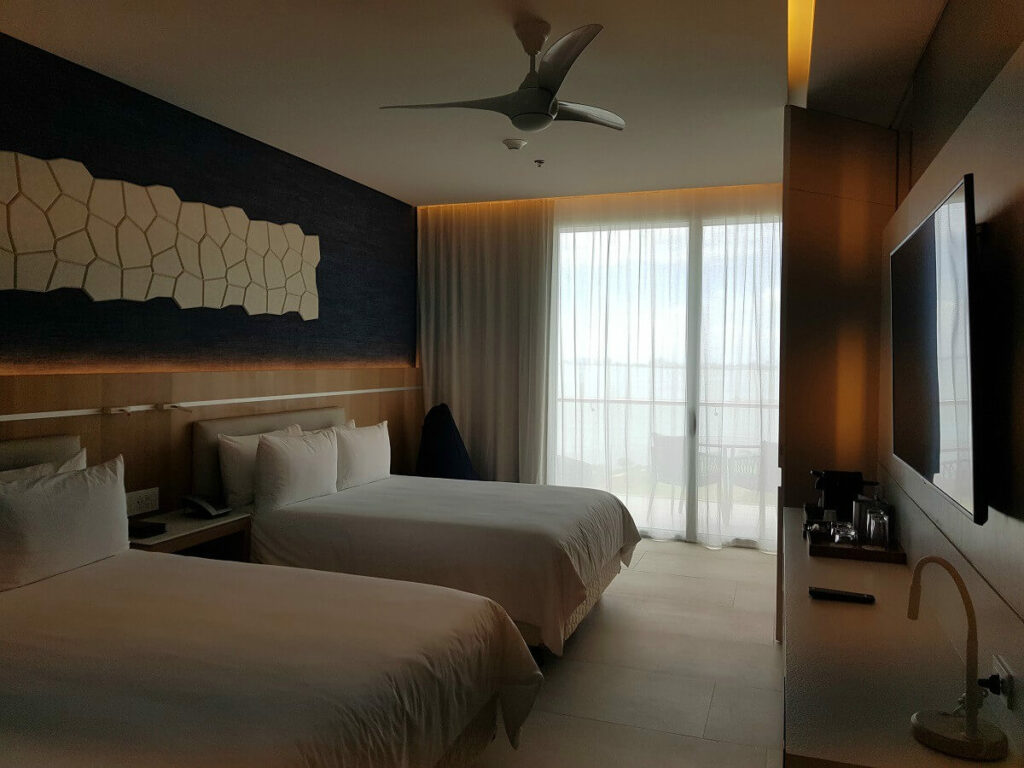 hotel room interior with two double beds, white bedding and blue wall