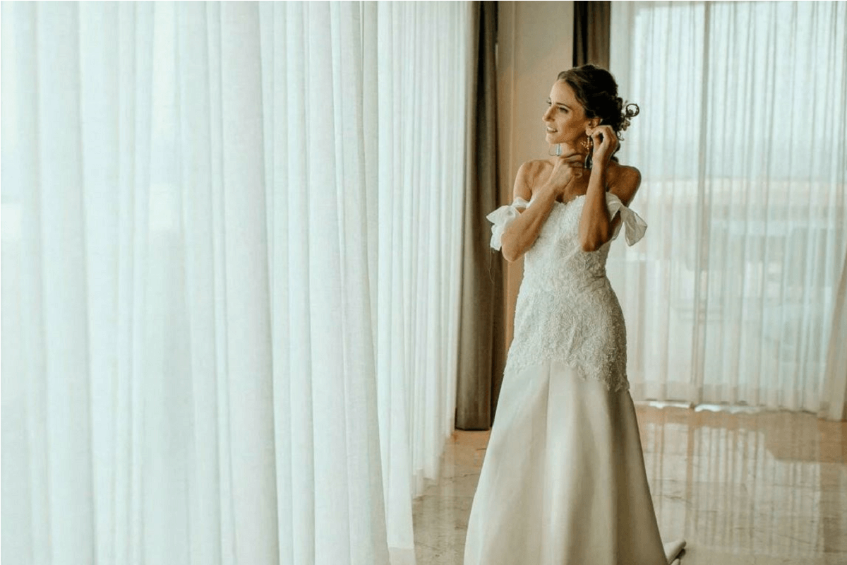 Bride arranging her earing looking through the window