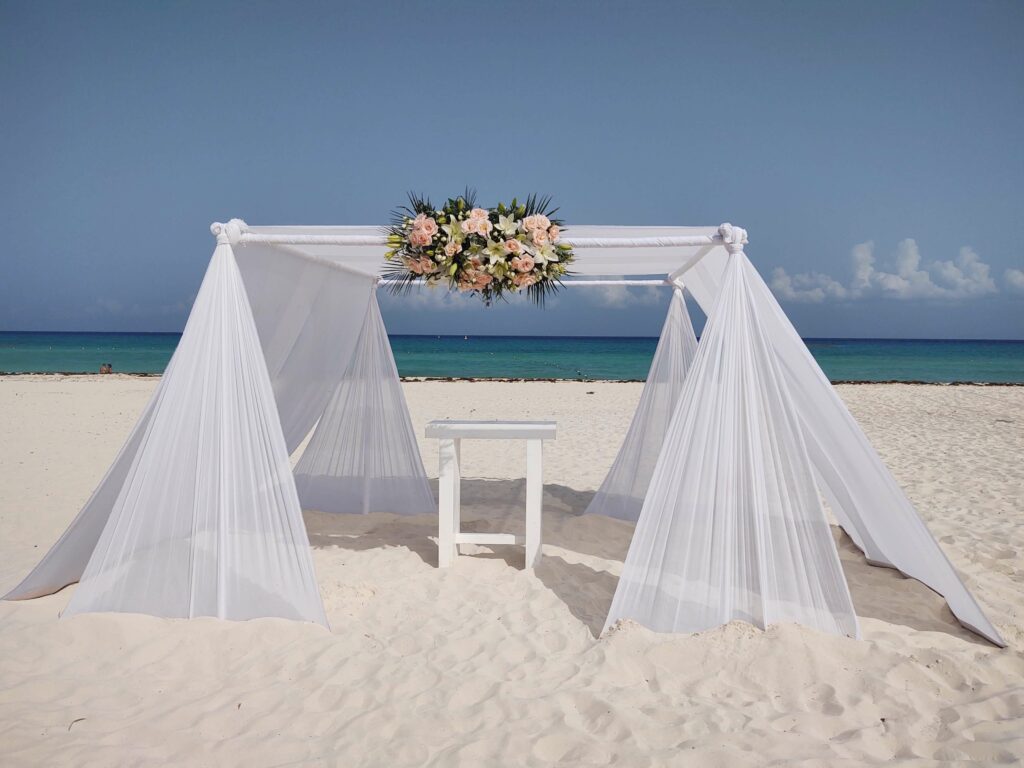 Destination wedding beach ceremony set-up with white pergola and drapes at the Sandos Playacar