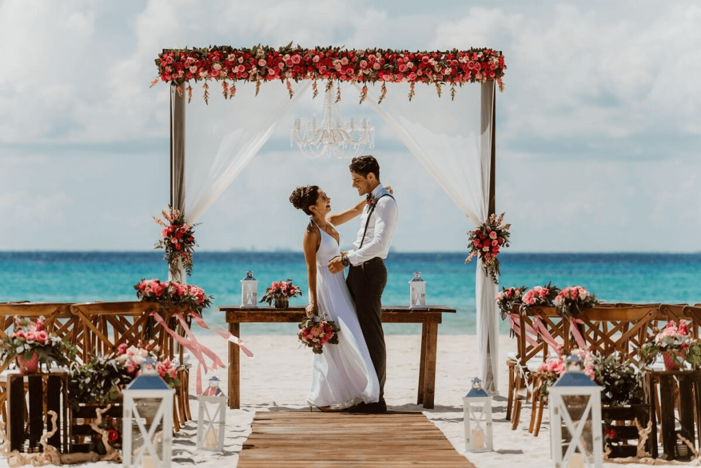 Couple gettin married on the beach with a flower arch
