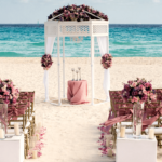 Destination wedding ceremony set-up with golden chairs and pink ribbons and flowers at the beach wedding gazebo of Iberostar Tucan/Quetzal