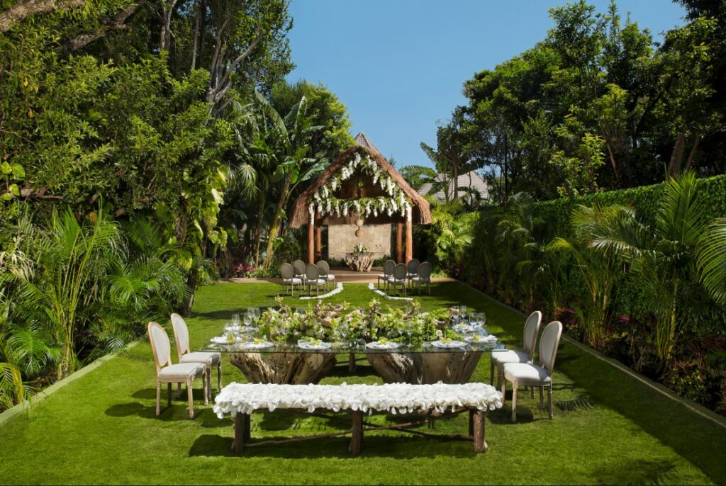 Lush tropical garden with palapa set for a private wedding with white flowers