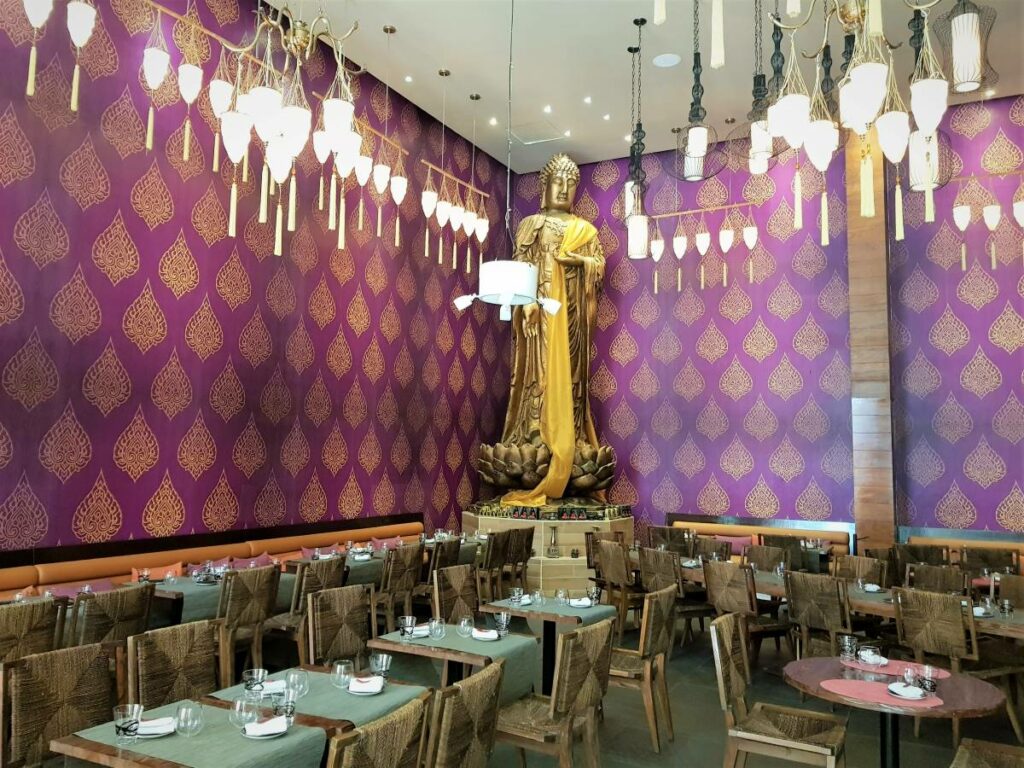 Thai restaurant with big buda sculpture and purple walls and chandeliers