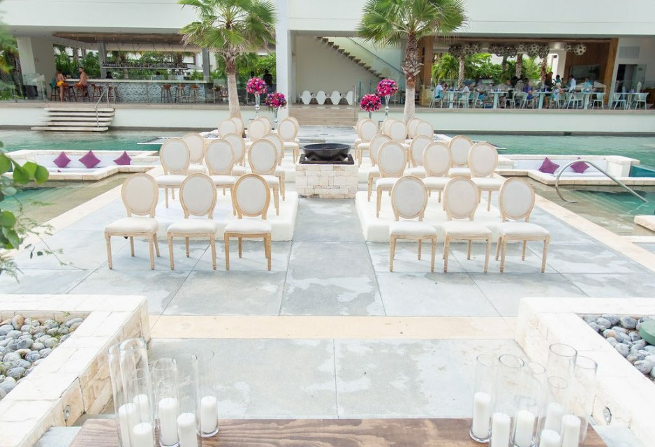 Pool terrace set for a wedding reception with white chairs