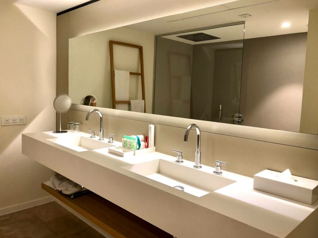 Minimalist hotel room bathroom with double vanities and bulgary amenities