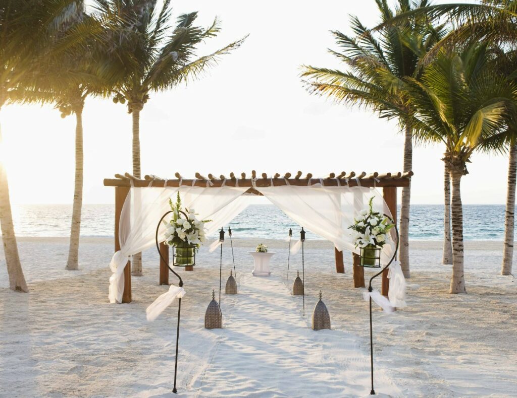Beach wedding set up with a wooden pergola and torches