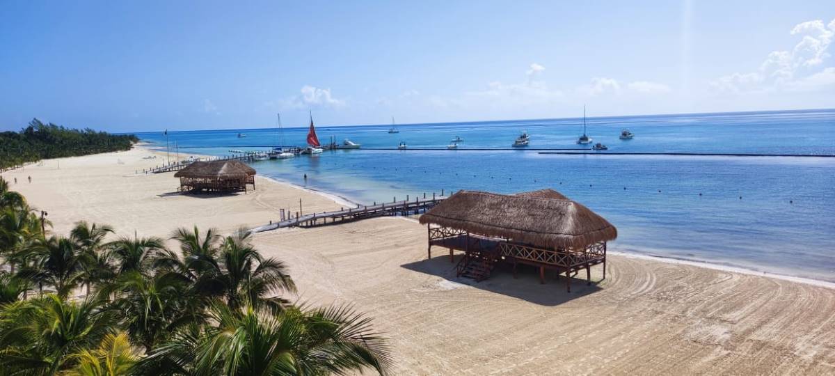 Expansive caribbean beach with a deck and palapa roofs