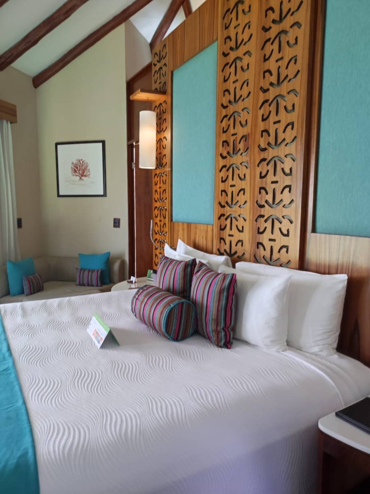 Hotel suite with a king size bed and colored cushions and wooden details