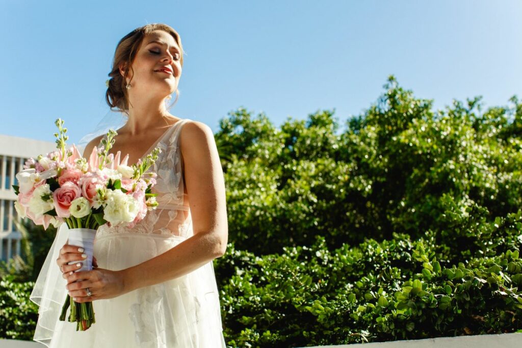 Mariée souriante tenant son bouquet de fleurs dans un jardin luxuriant