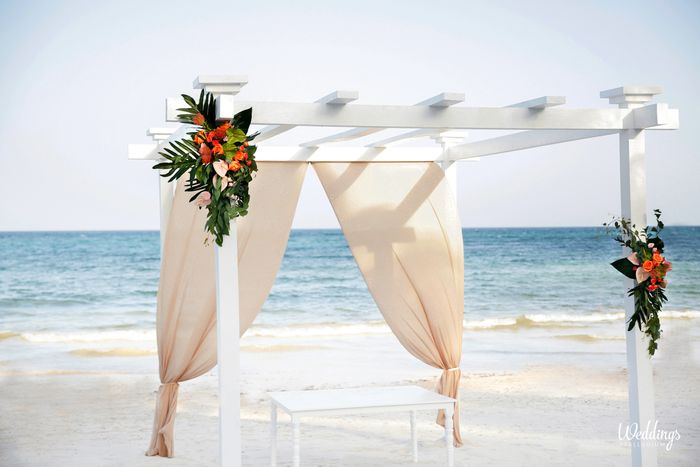 Ocean front white wedding pergola with nude drapes and tropical flowers
