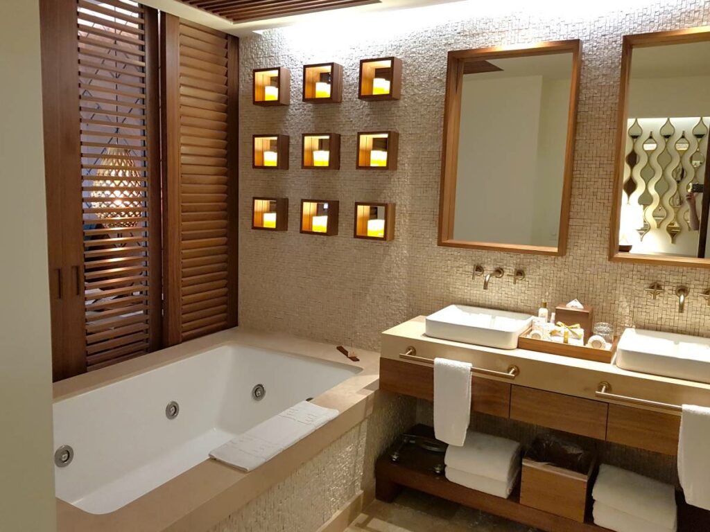 Hotel room bathroom with bathtub, double vanities and little candle lamps