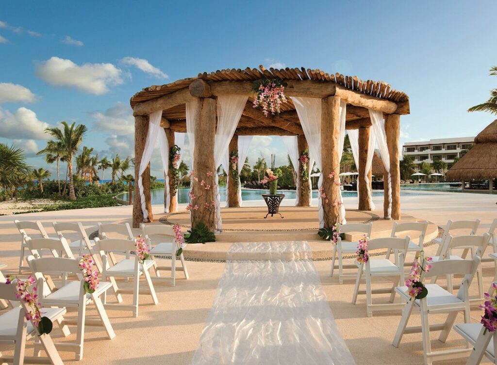 Wedding gazebo with white drapes, pink flowers and white chairs