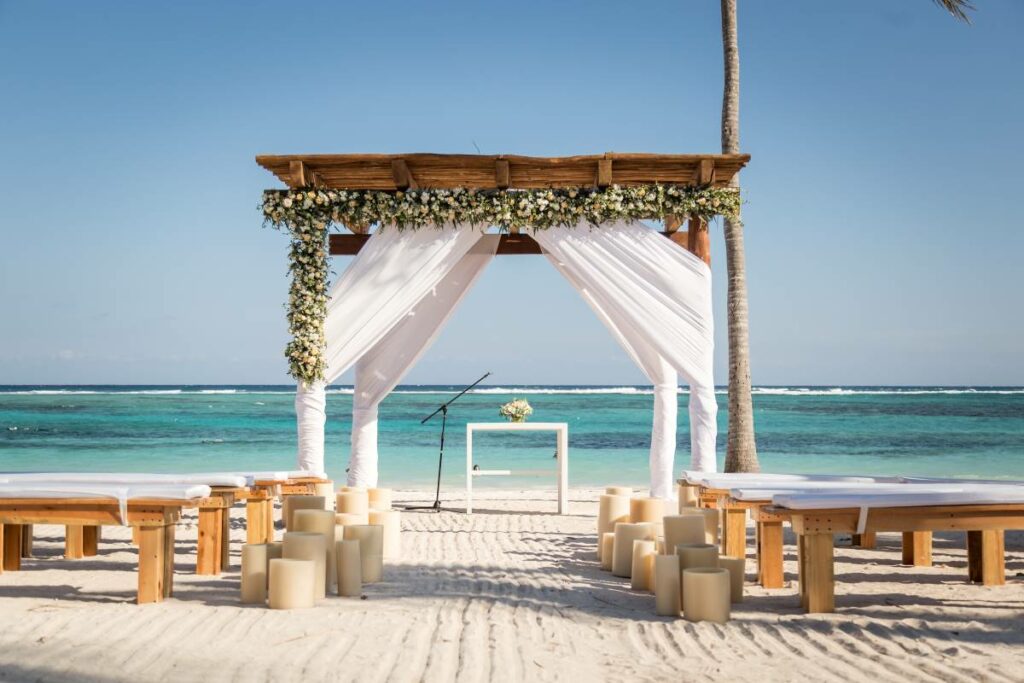 Oceanfront wedding gazebo with white drapes, flowers and wooden benches
