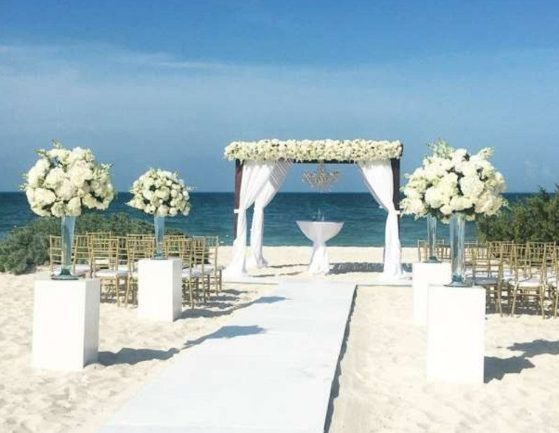 Beach wedding set up with white flowers and gold chairs