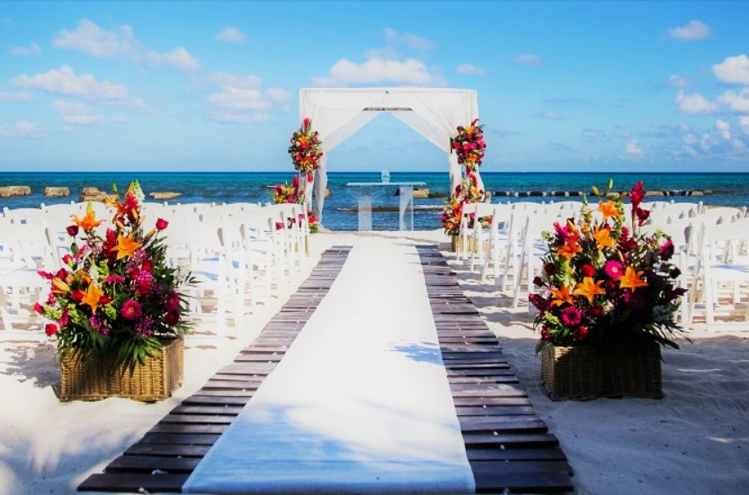 Beach wedding gazebo with white drapes and tropical flower arrangements