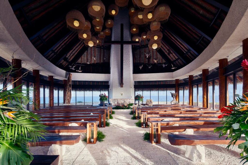 Catholic chapel with palapa roof, wooden benches and big windows with ocean view