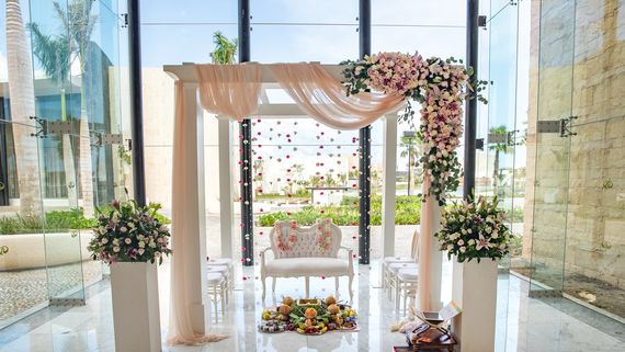 wedding area with big glass windows and a pergola with pink drapes and pink flowers