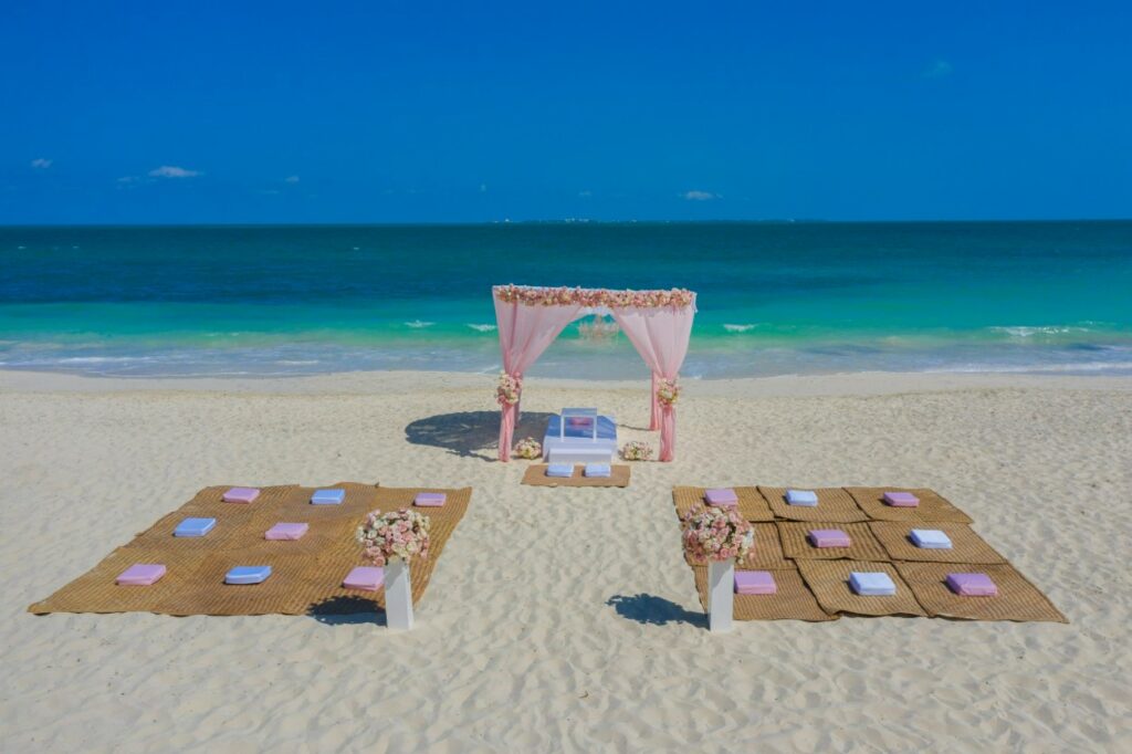 Wedding gazebo on the beach with pink drapes and white and pink pillows