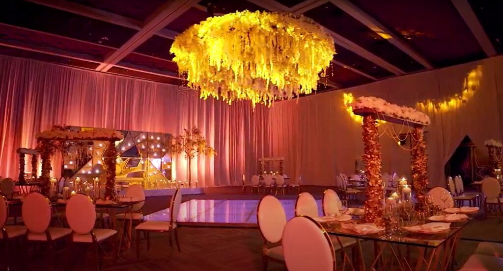 Wedding set up in a ballroom with hanging yellow flowers and a led light dancefloor