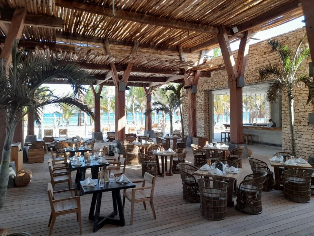 Outdoor restaurant with beach view, and wooden furniture