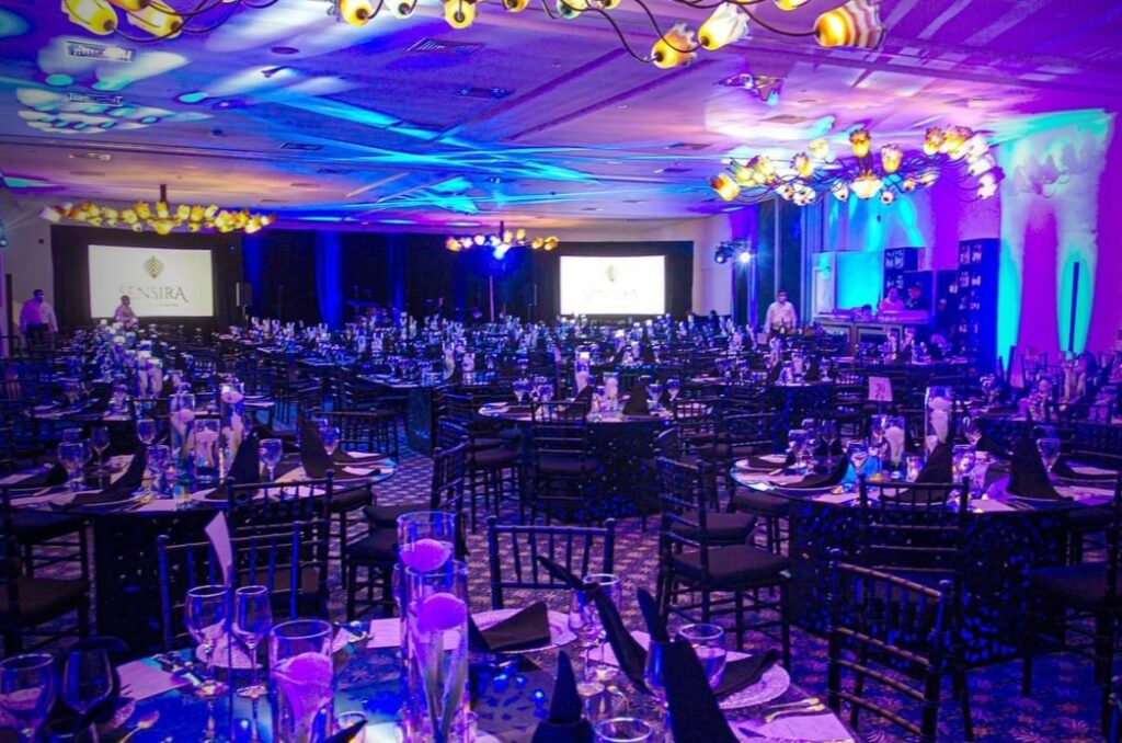 Resort ballroom set up for a wedding with black chairs and purple lighting