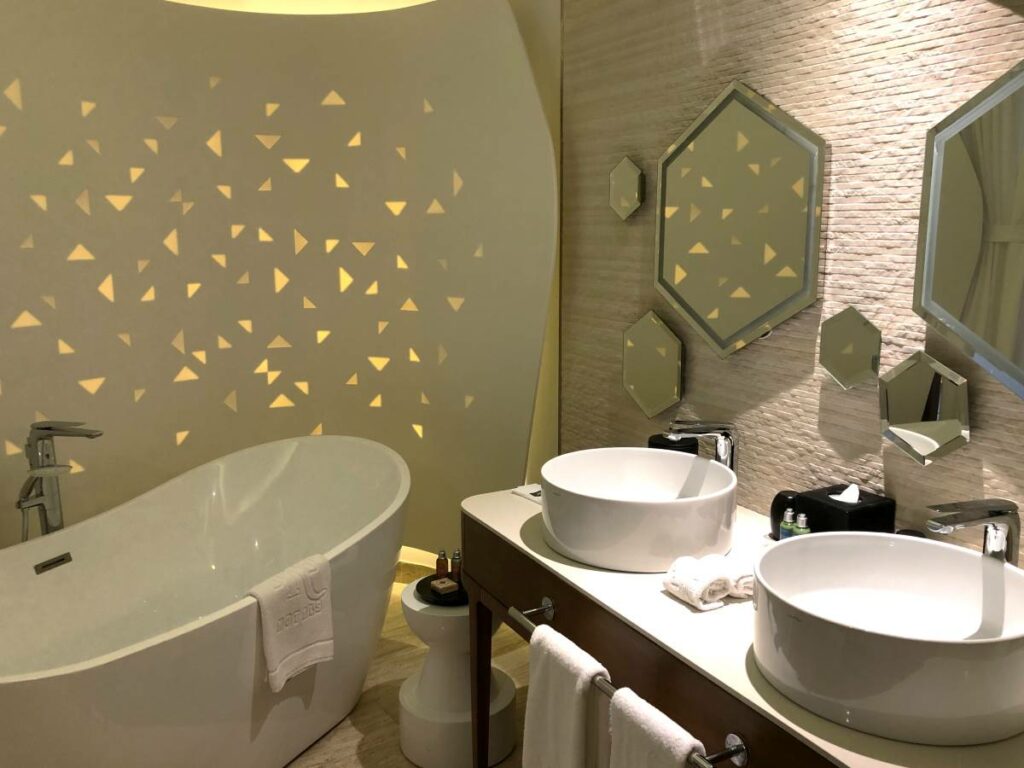 Hotel bathroom with two double vanities, large tub and hexagonal mirrors