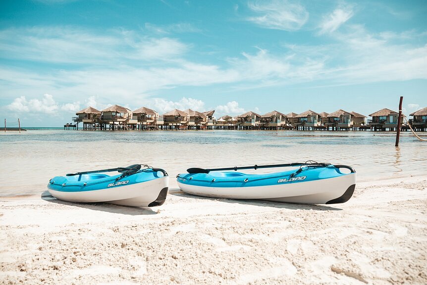 Kayaks on the beach with over the water bungalows on the background