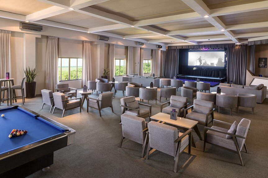 Hotel theatre with pool tables and a stage with a screen