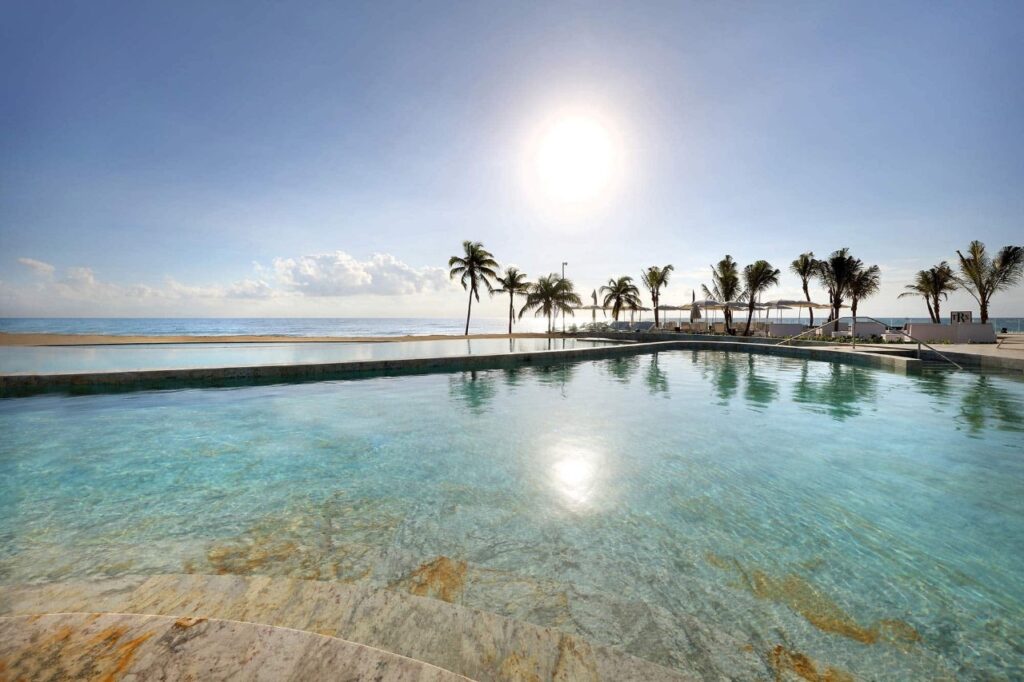 La piscine à débordement d'une station balnéaire avec des palmiers est un moyen de réduire les coûts d'un mariage à destination