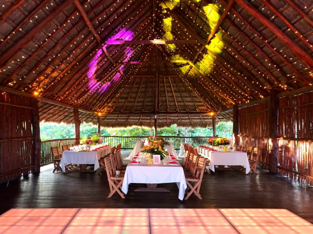 Wedding reception set in a palapa roof salon with string lights and dance floor with led lights