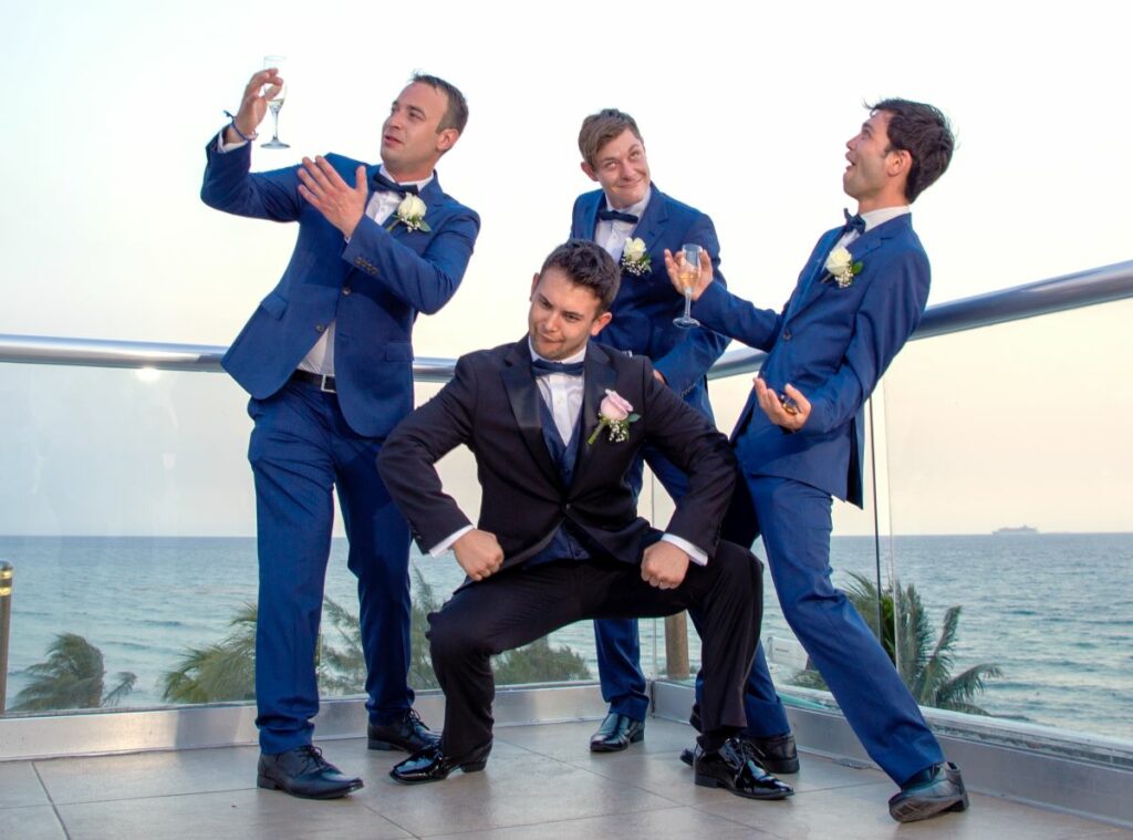 Groom with groomsmen dressed in blue doing funny poses for the photographer