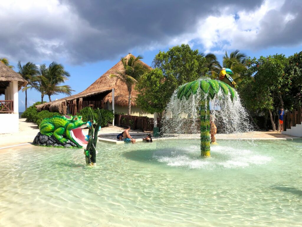 Kids water playground with a palmtree with water jets and animals