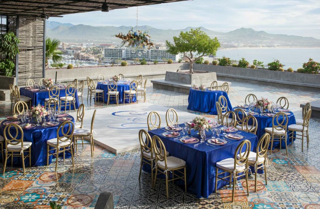Wedding set up in blue and gold set up on a rooftop terrace with view of the ocean and mountains