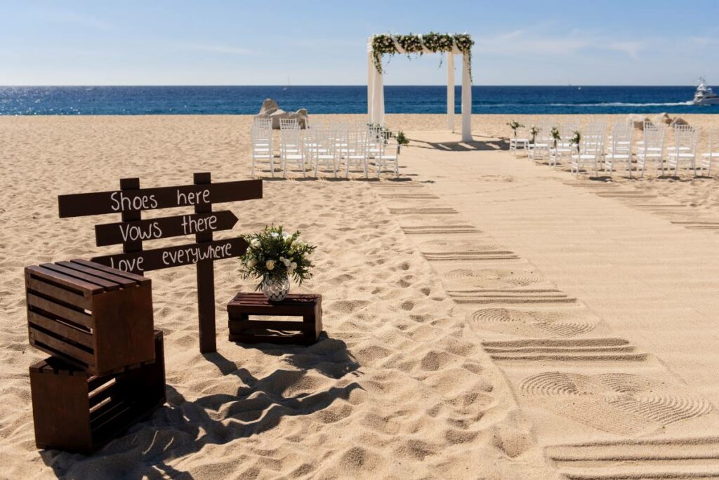 Cérémonie de mariage sur la plage avec une pergola blanche et une station de chaussures