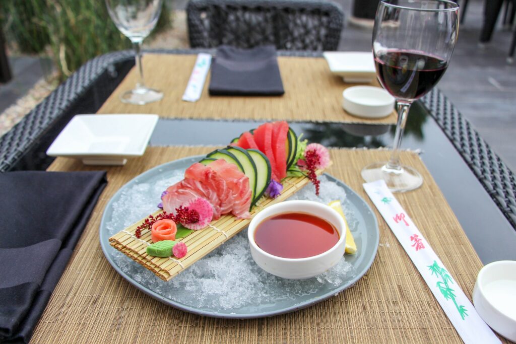 Asian dish with tuna sashimi and cucumber and a glass of red wine