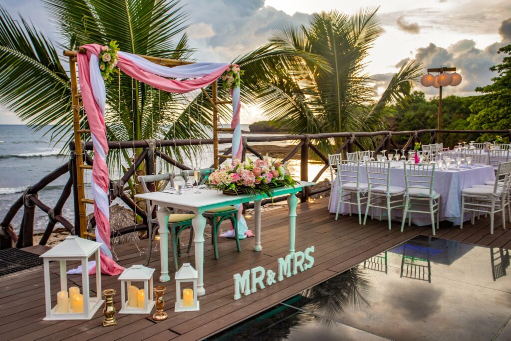 wedding set up at an ocean view deck with a mr and mrs sign and a frame with drapes