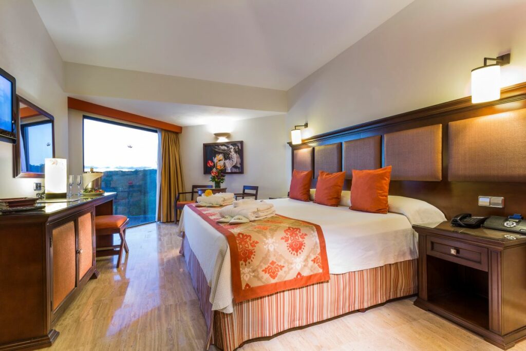 Hotel room with one king size bed, wooden furniture, sitting area and a large window