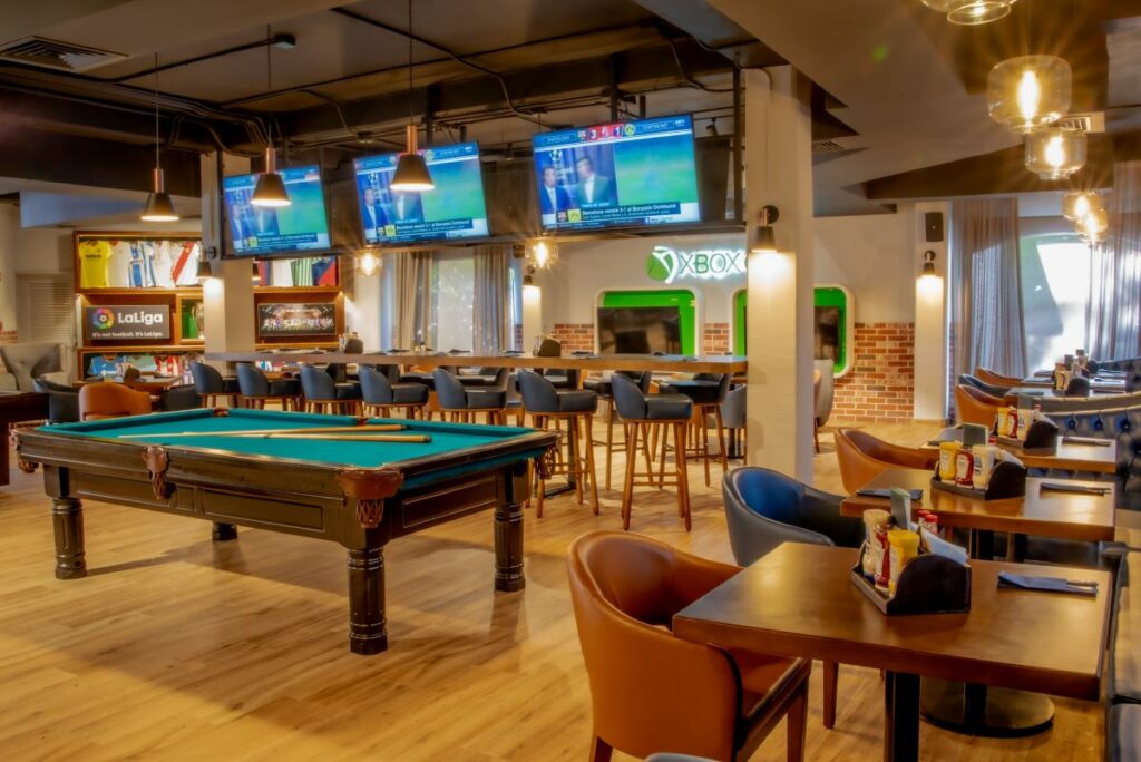 sports bar with pool table, stools and large screens